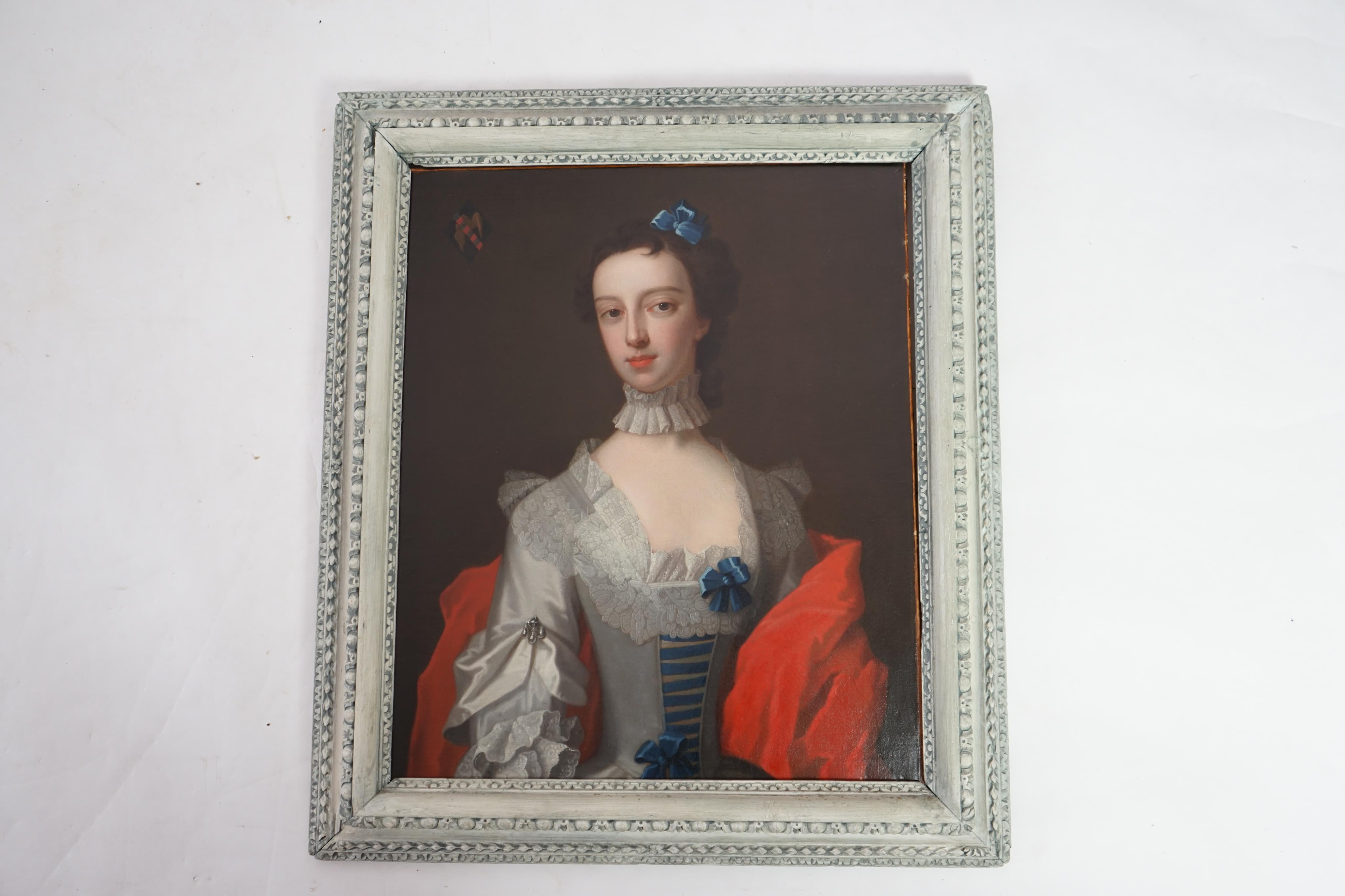 Attributed to Enock Seeman (c.1694-1745), Half length portrait of a lady with blue ribbon in her hair, elaborate lace collar and crimson robe, an armorial to the top left, oil on canvas, 74 x 62cm